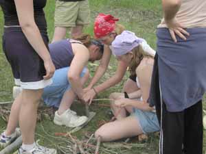 Team effort to start a bow and drill fire.