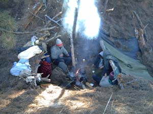 Two lean-to ponchos for camping near fire.