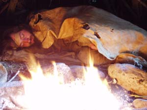 Sleeping by fire under buckskin blanket.