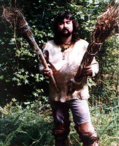 Man in buckskins holding primitive torches.